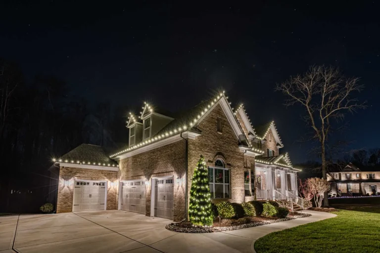 Warm white Christmas lights on a gabled Atlanta-area home with a lit front-yard tree.