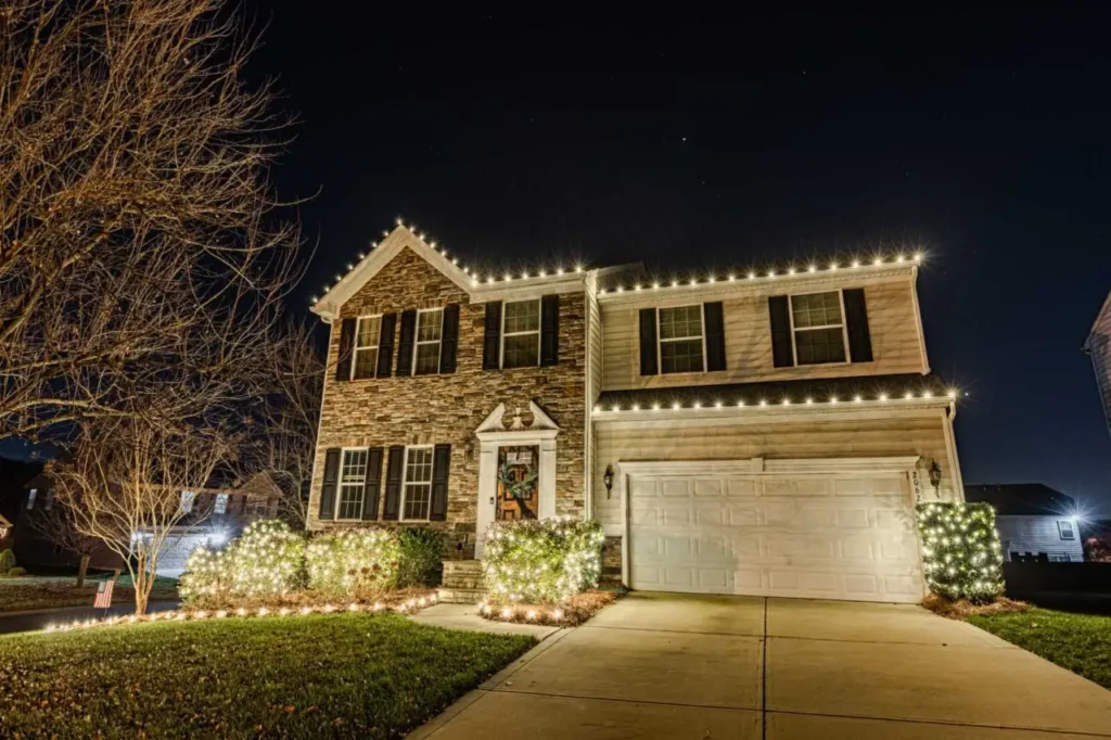 Warm white holiday lights outlining the roofline and garage of an Atlanta-area home.