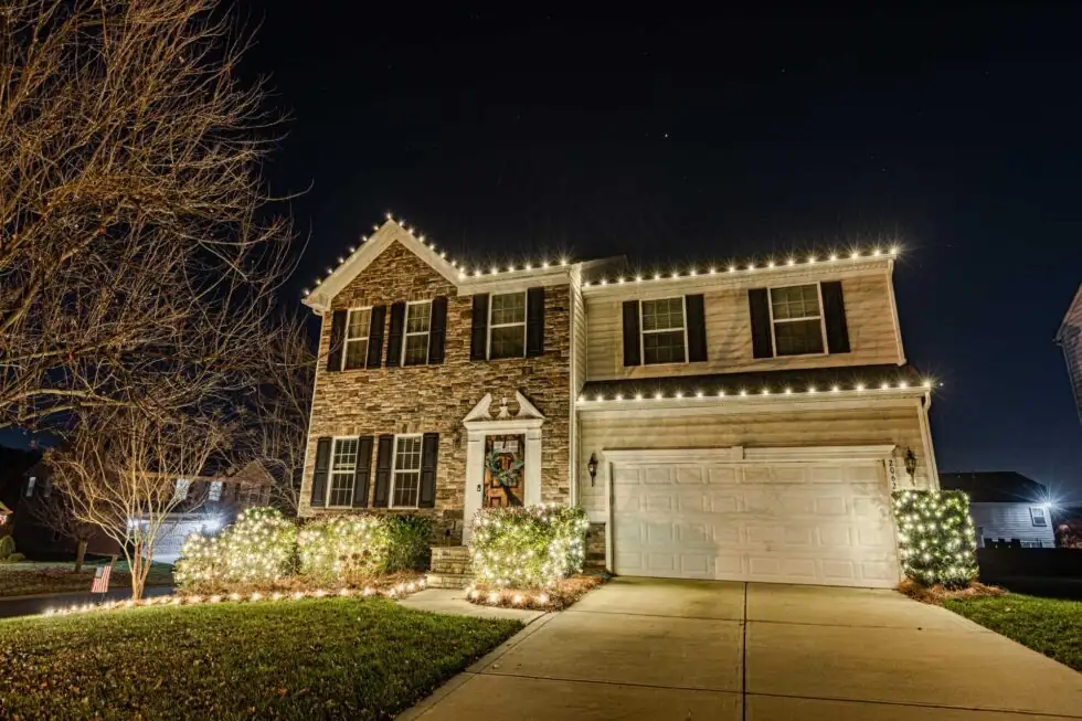 Warm white holiday lights outlining the roofline and garage of an Atlanta-area home.